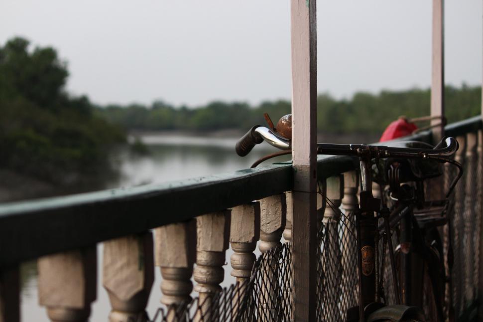 Free Image of Bicycle Leaning Against Fence by Water 