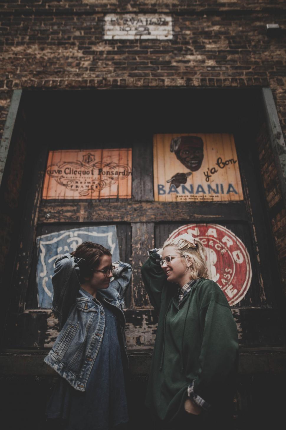 Free Image of Two Women Standing in Front of a Brick Building 