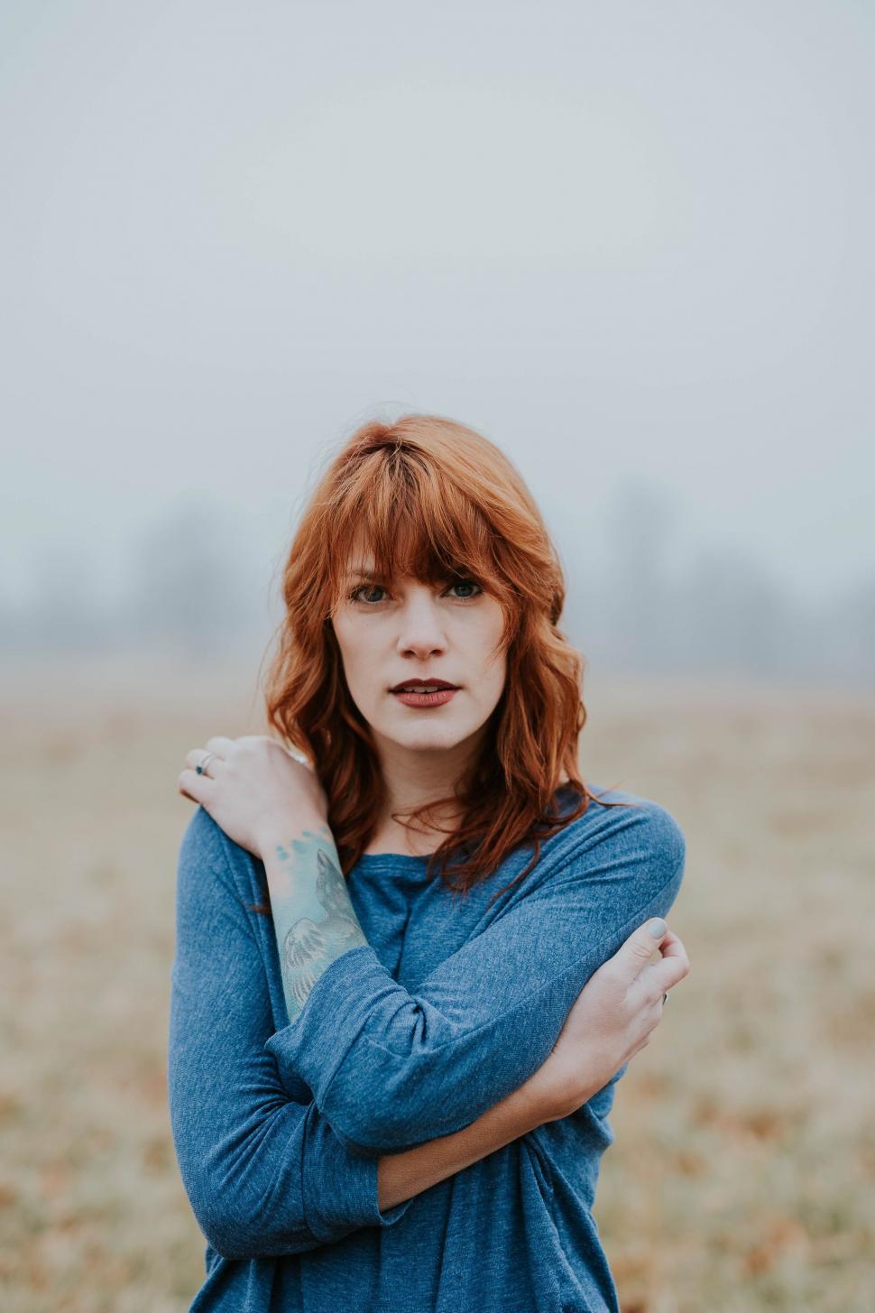 Free Image of Woman Standing in a Field With Arms Crossed 