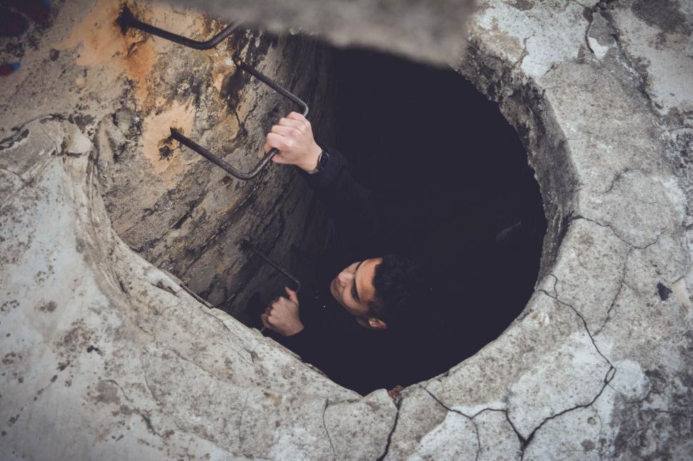 Free Image of Man Holding Umbrella in Ground Hole 