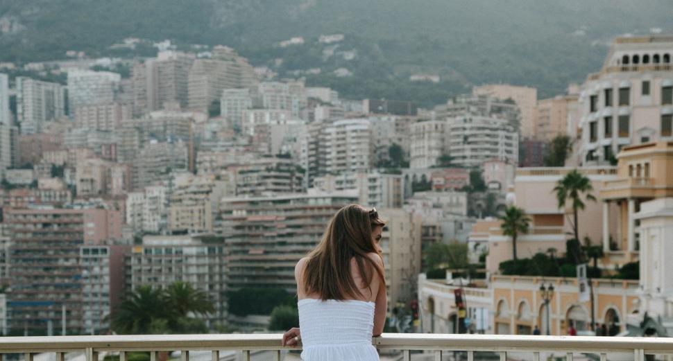 Free Image of Woman in a White Dress Standing on a Balcony 