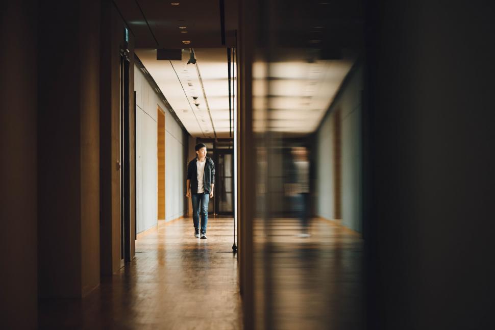 Free Image of Man Walking Down Hallway in Building 