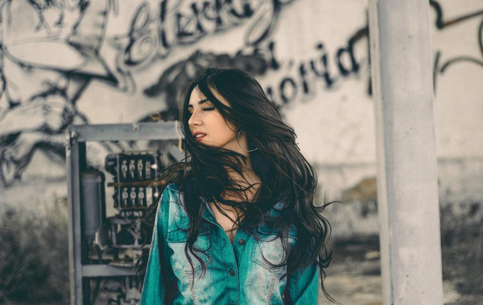 Free Image of Woman Standing in Front of Graffiti Covered Wall 