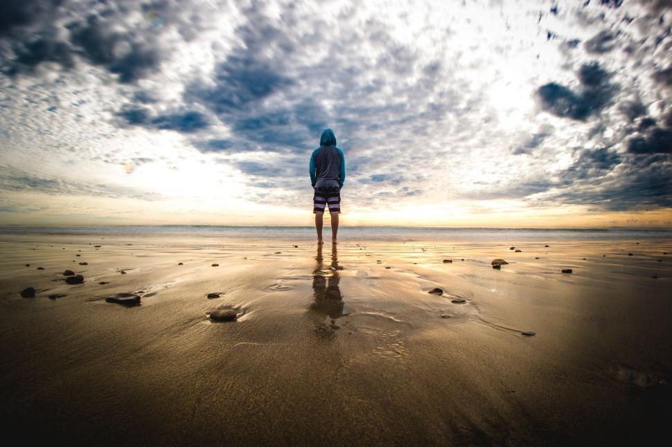 Free Image of Person Standing on Beach Under Cloudy Sky 
