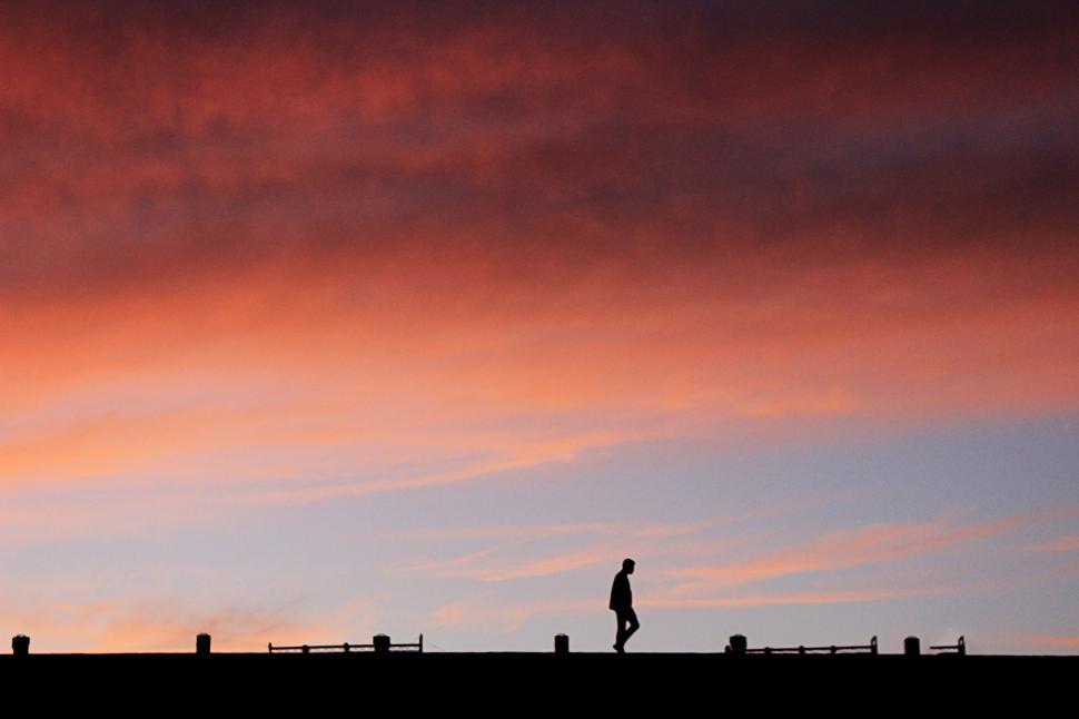 Free Image of Person Walking Across Field Under Cloudy Sky 