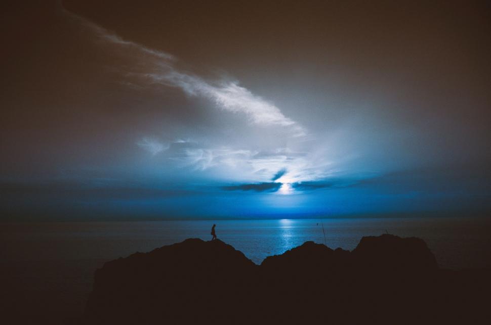 Free Image of Person Standing on Top of Mountain Under Cloudy Sky 