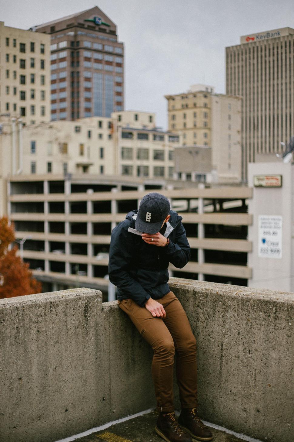 Free Image of Man Sitting on Ledge Talking on Cell Phone 