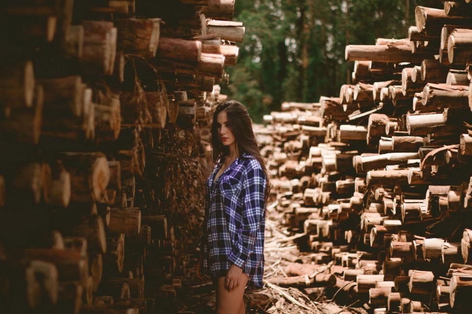 Free Image of Woman Standing in Front of Pile of Logs 