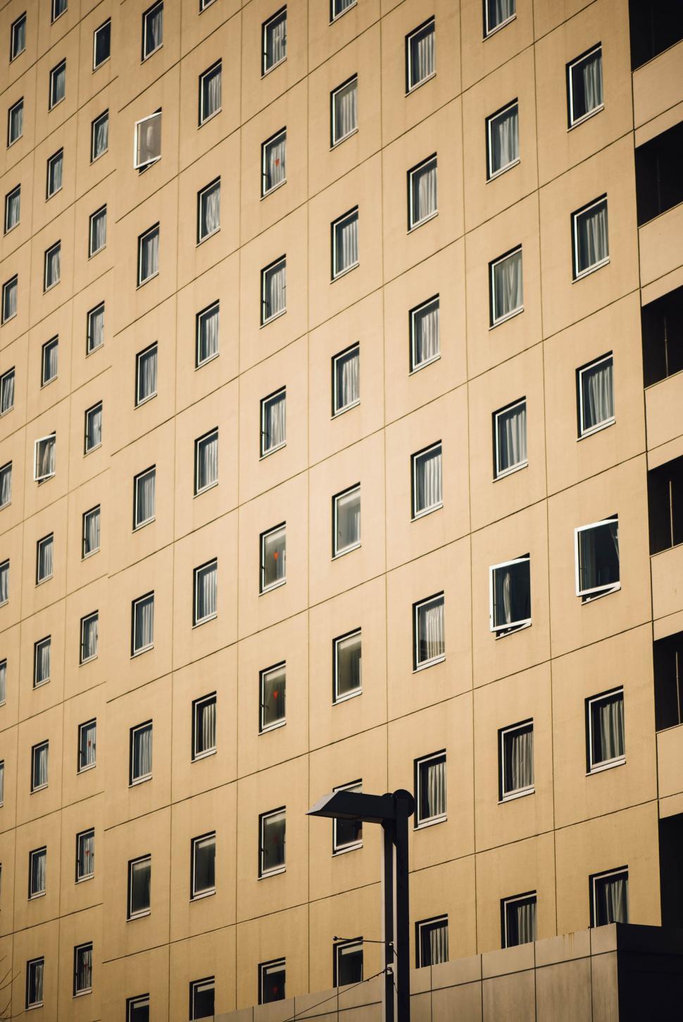 Free Image of Tall Building With Many Windows Next to Street Light 