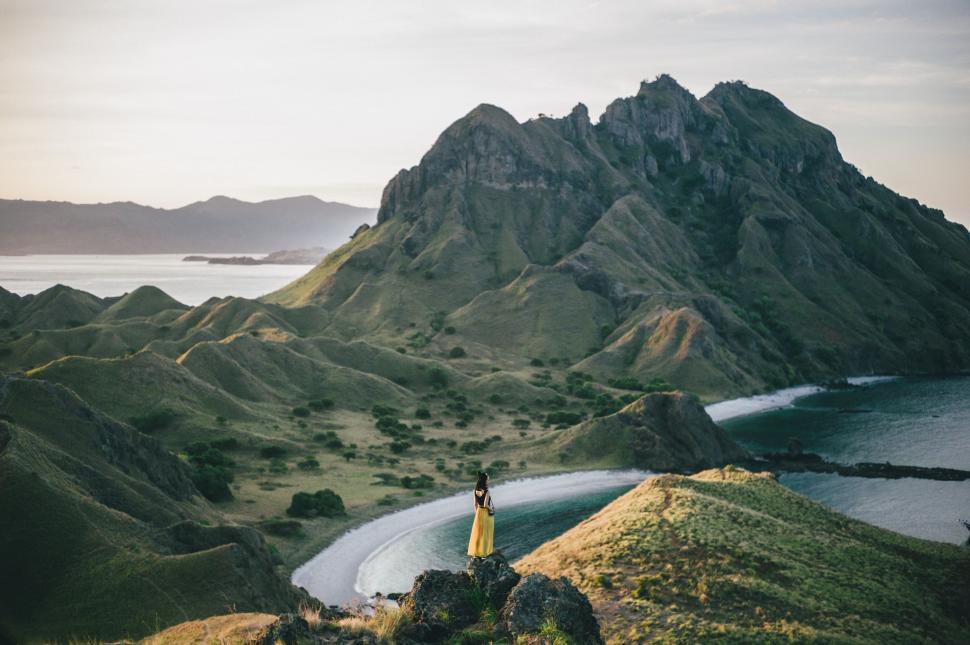 Free Image of Person Standing on Top of Hill Overlooking Body of Water 