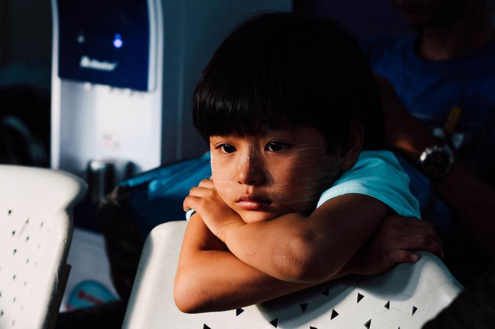 Free Image of Young Boy Sitting in Chair With Arms Crossed 