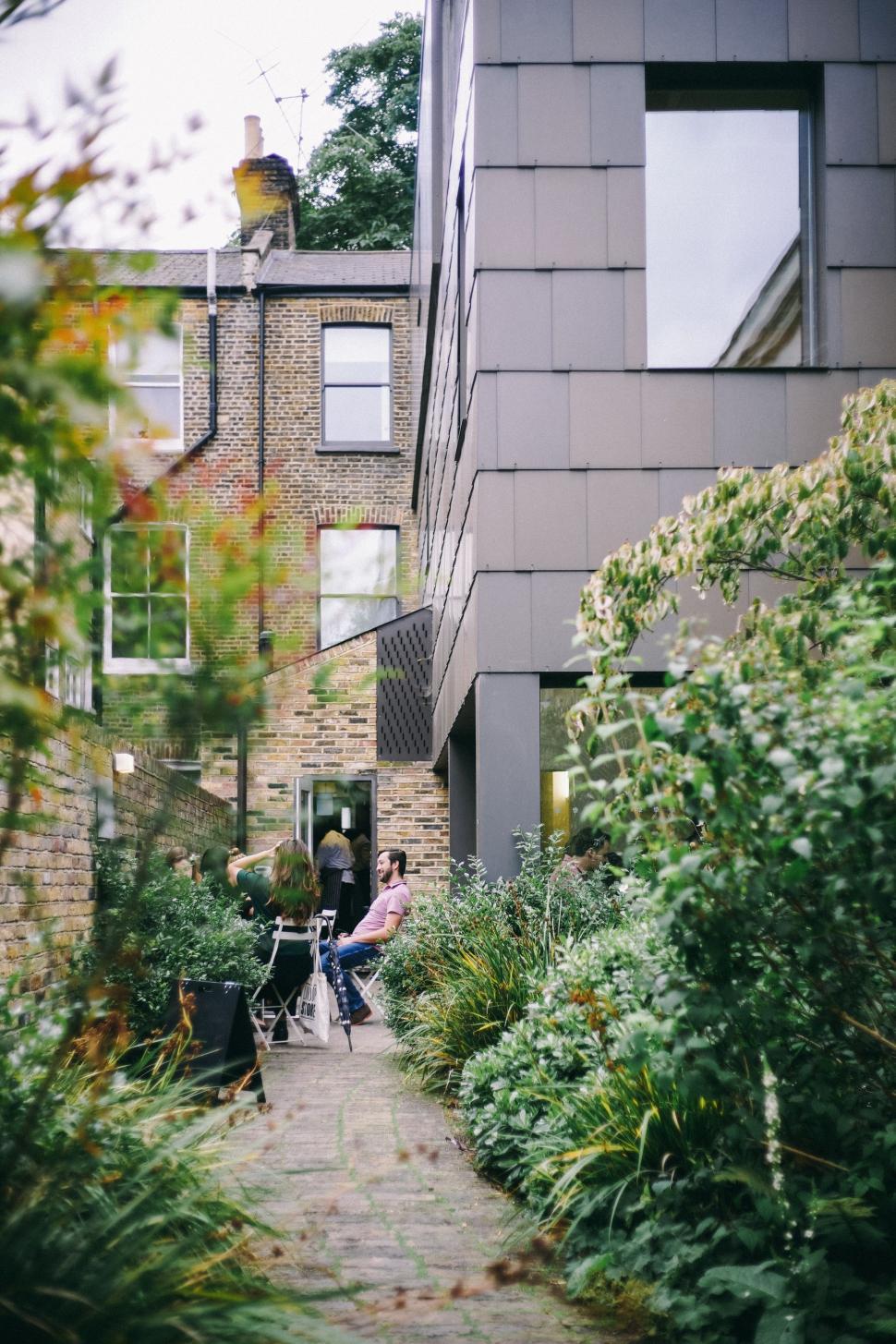 Free Image of Woman Walking Down Sidewalk Next to Tall Building 