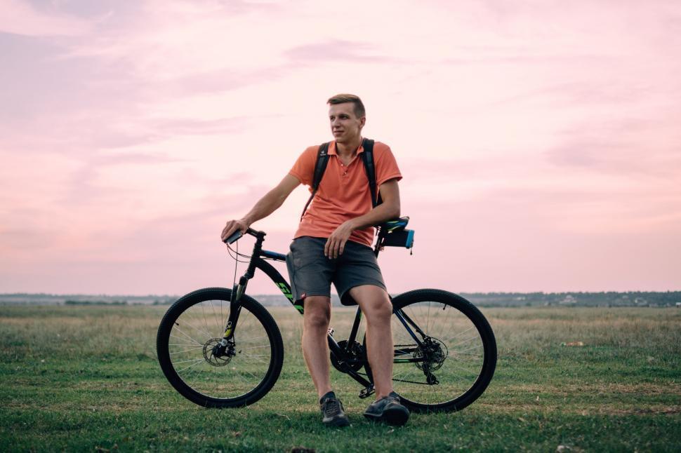 Free Image of Man Standing Next to Bike in Field 