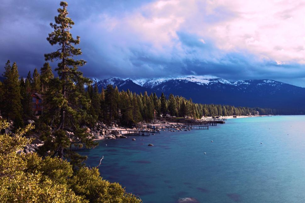Free Image of Lake Surrounded by Trees and Mountains Under Cloudy Sky 