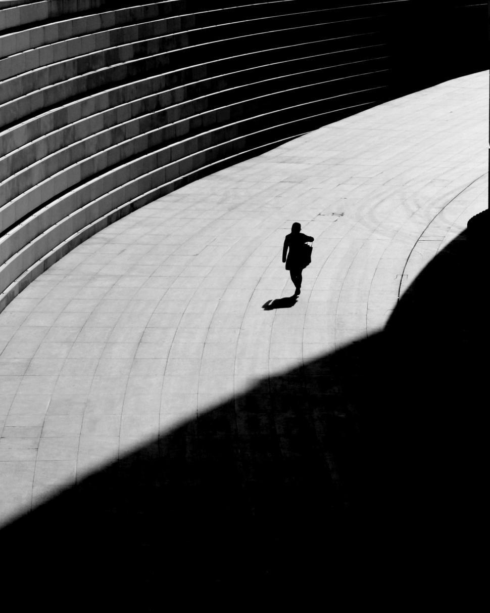Free Image of Person Walking Down Street Under Bridge 