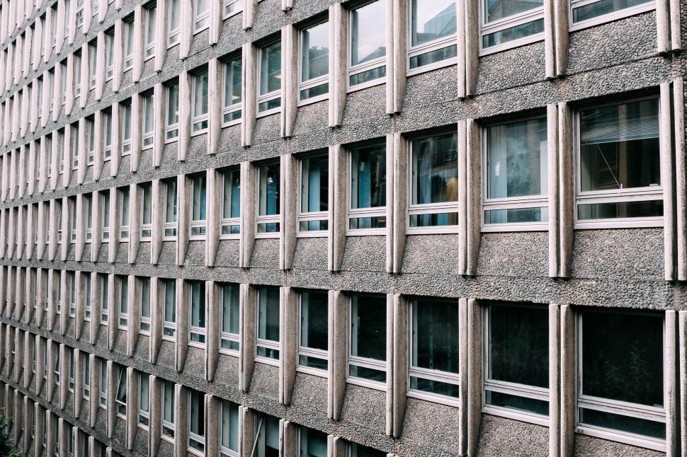 Free Image of Tall Building With Many Windows Next to Busy Street 