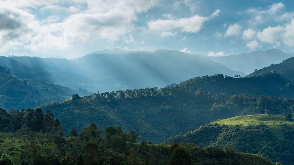 Free Image of Sun Shines Through Clouds Over Mountains 
