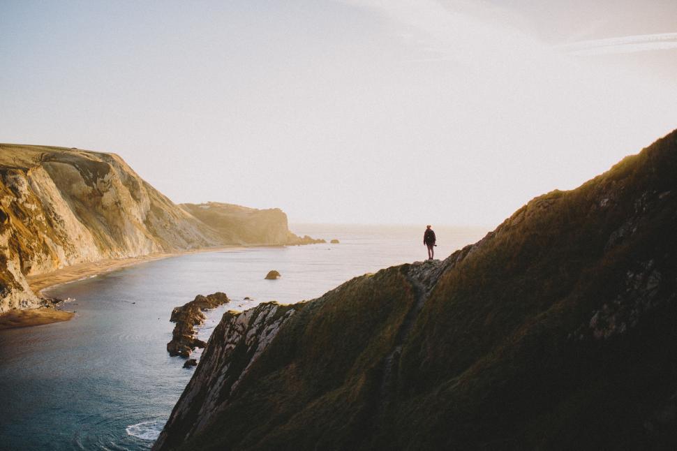 Free Image of Person Standing on Cliff Overlooking Body of Water 