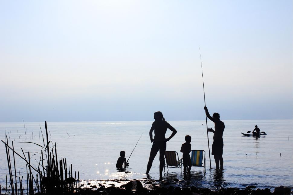 Free Image of Group of People Standing on Top of Body of Water 