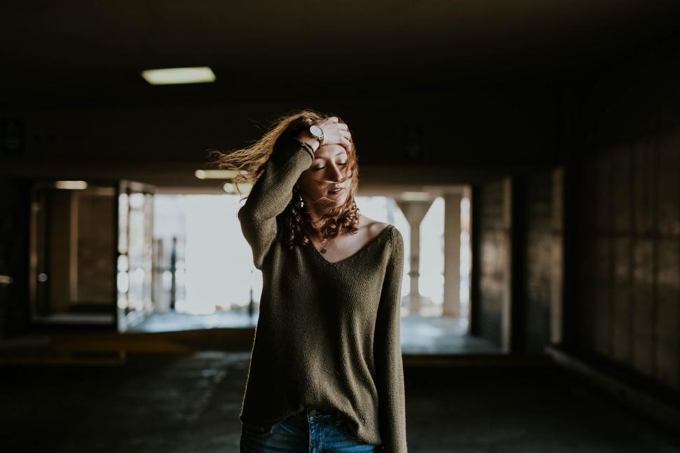 Free Image of Woman Standing in Dark Hallway With Hair Blowing 