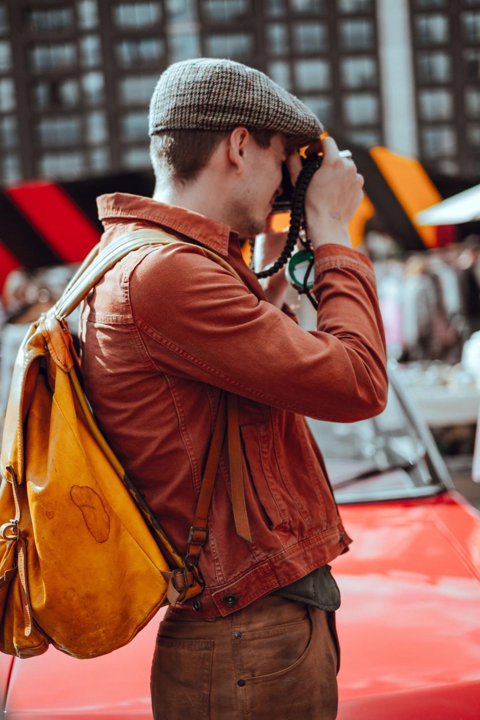 Free Image of Man Talking on Cell Phone Next to Red Car 