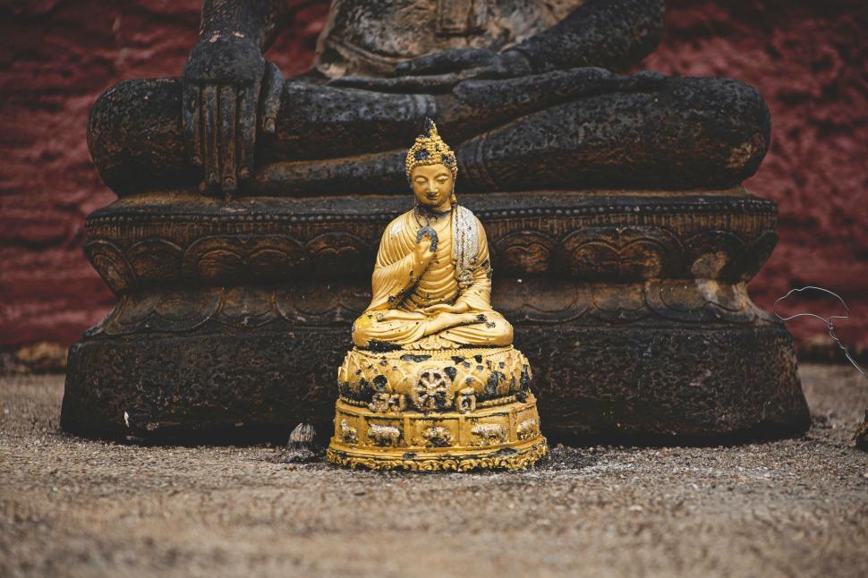 Free Image of Buddha Statue Sitting in Front of Red Wall 