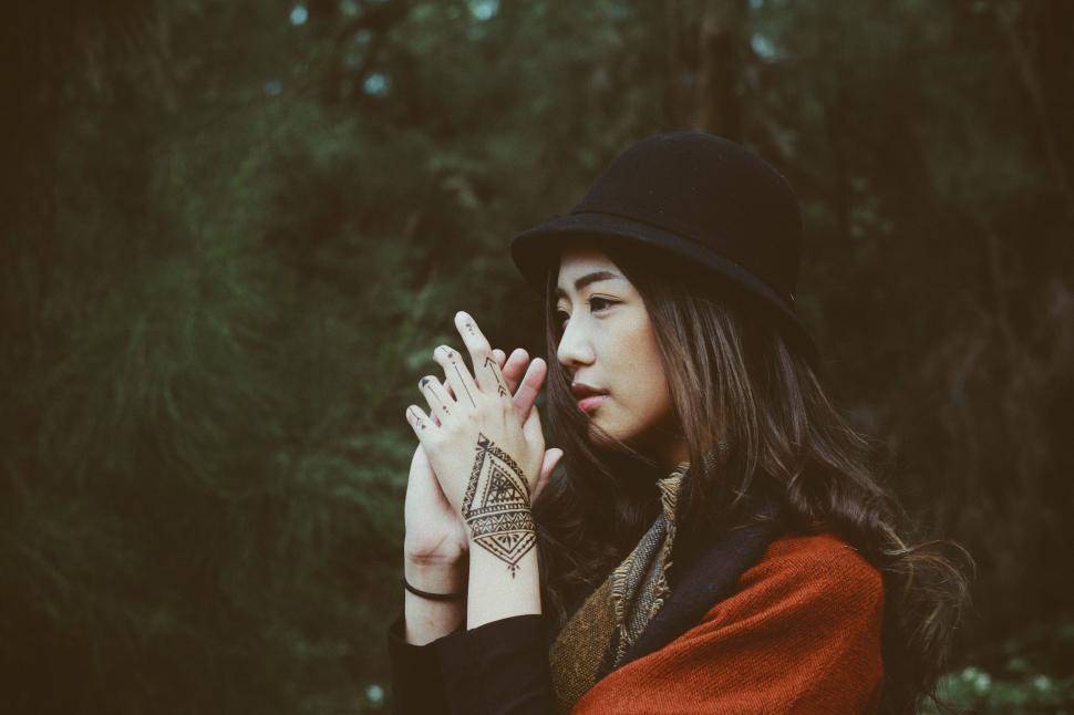 Free Image of Woman in Hat and Scarf Holding Hands Together 