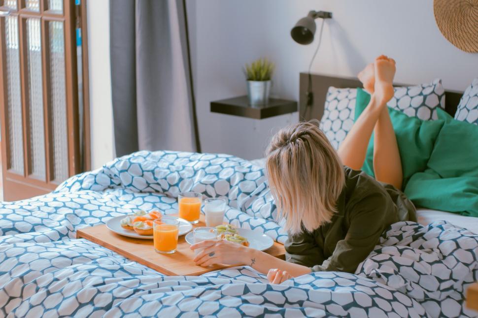 Free Image of Woman Laying on Bed With Tray of Food 