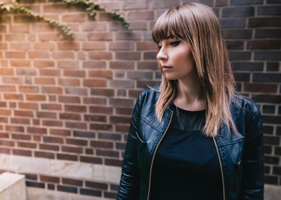 Free Image of Woman Standing in Front of Brick Wall 