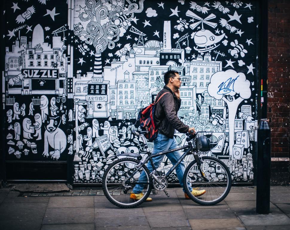 Free Image of Man Walking Bike With Backpack 