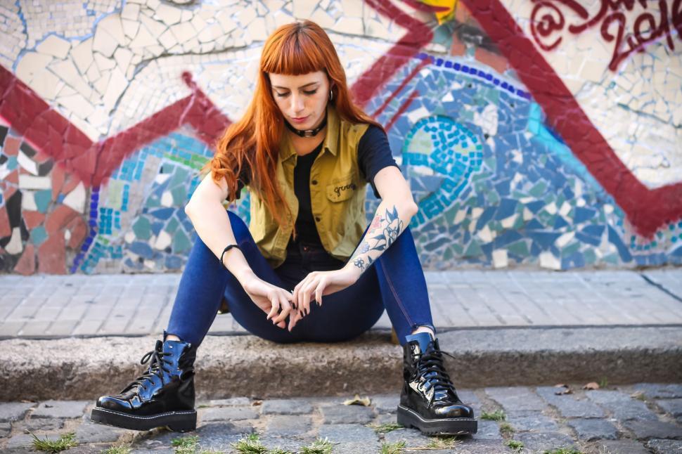 Free Image of Woman Sitting in Front of Graffiti Wall 