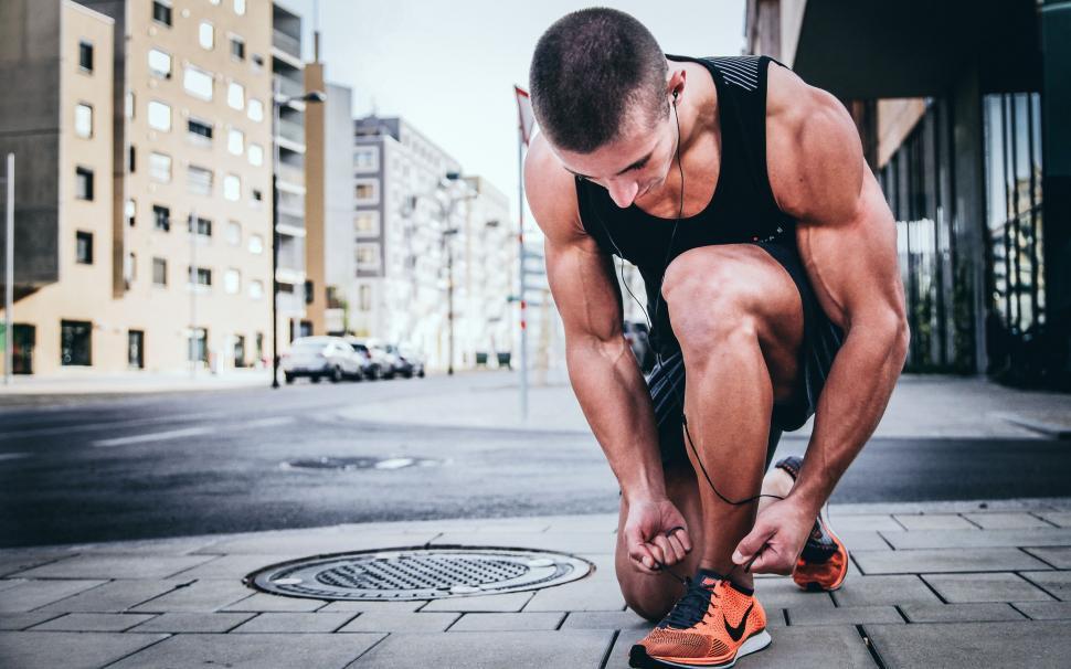 Free Image of Man Tying His Shoes on City Street 