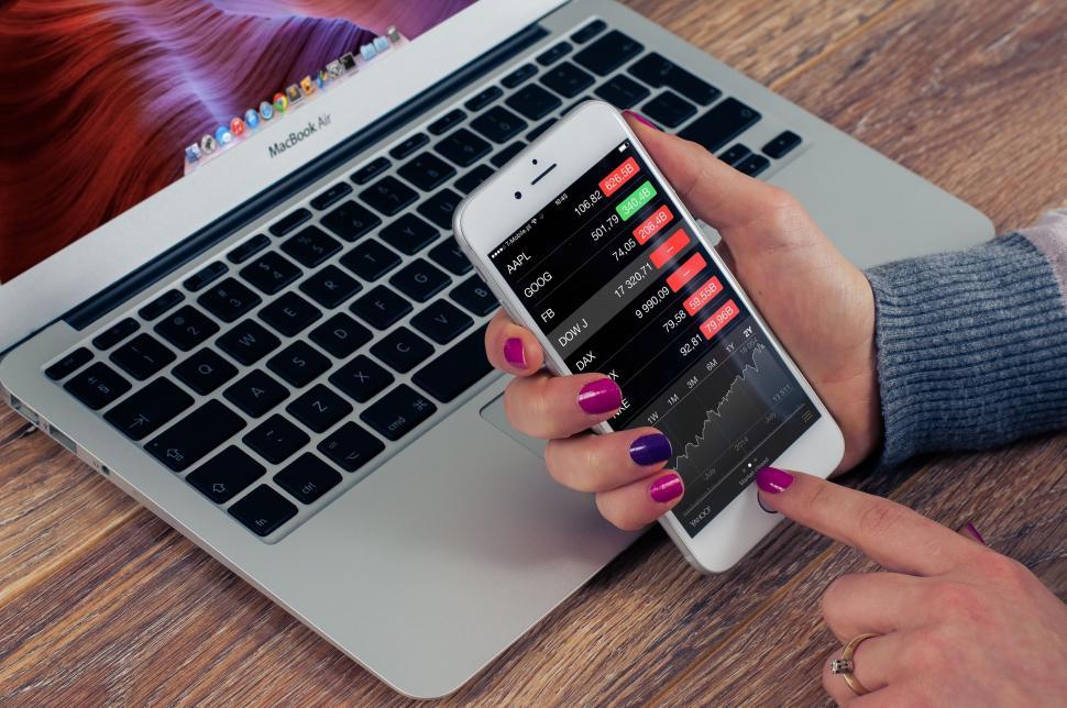 Free Image of Woman Using Cell Phone While Sitting in Front of Laptop 