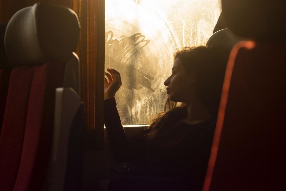 Free Image of Woman Sitting on Train Looking Out Window 