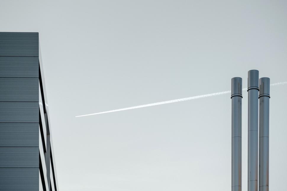 Free Image of Jet Flying Over Tall Building With Sky Background 