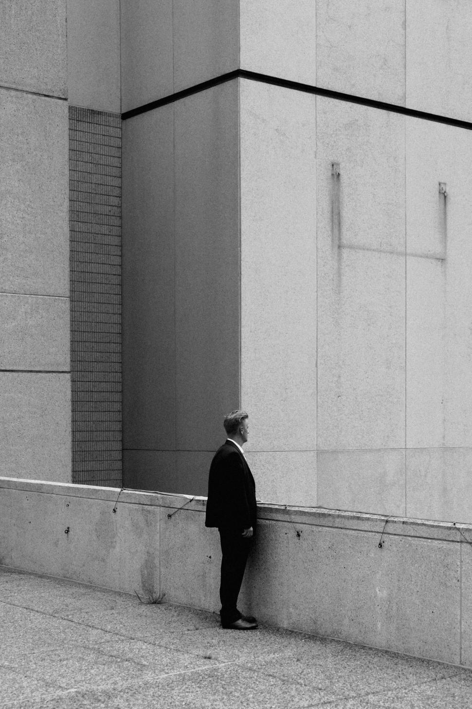 Free Image of Businessman Leaning Against Wall in Suit 