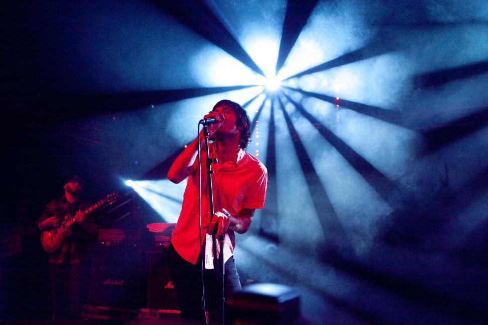 Free Image of Man Standing on Stage Holding Microphone 