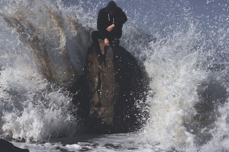 Free Image of Person Sitting on Top of Rock in Ocean 