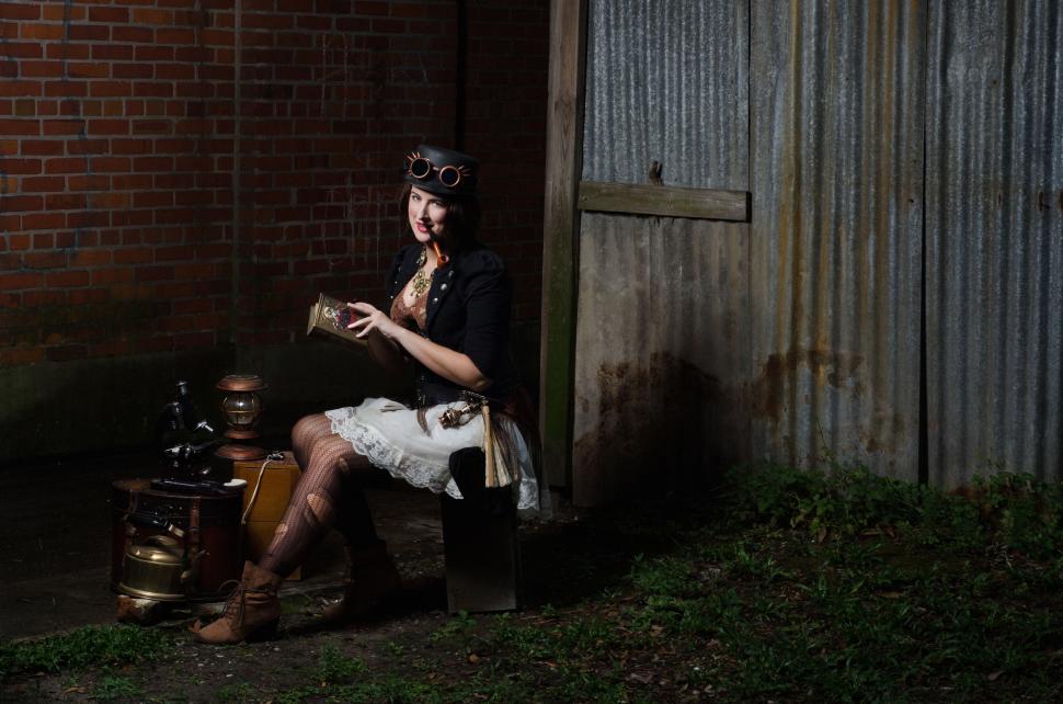 Free Image of Woman Sitting on Chair Next to Brick Building 