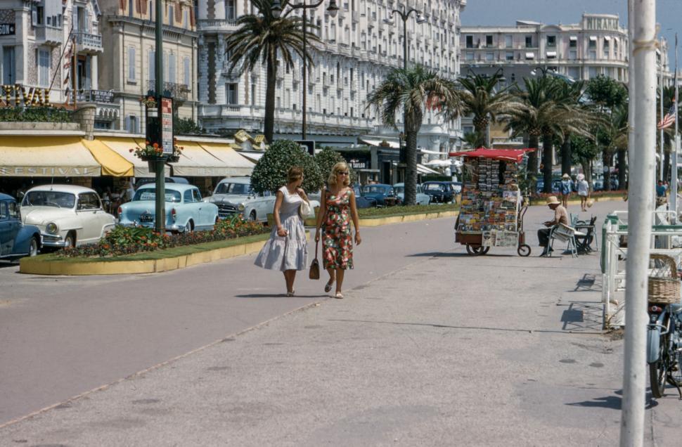 Free Image of Two Women Walking Down Street Next to Tall Buildings 