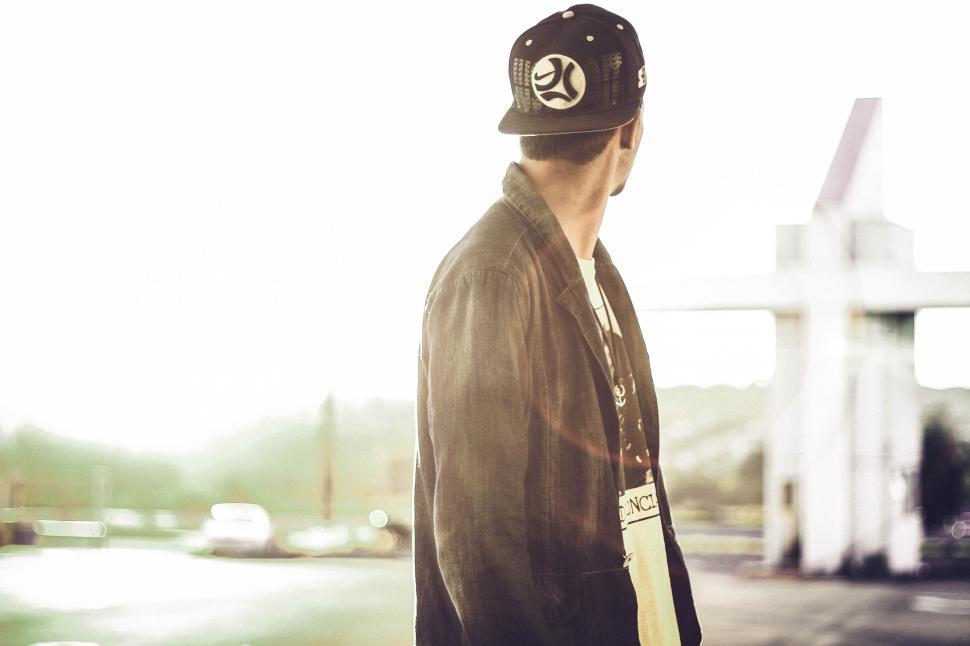 Free Image of Man Wearing Hat Standing in Front of Gas Station 
