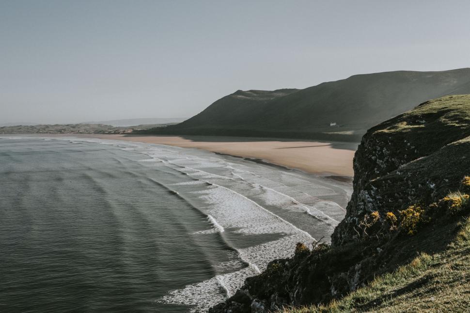 Free Image of Large Body of Water Next to Lush Green Hillside 