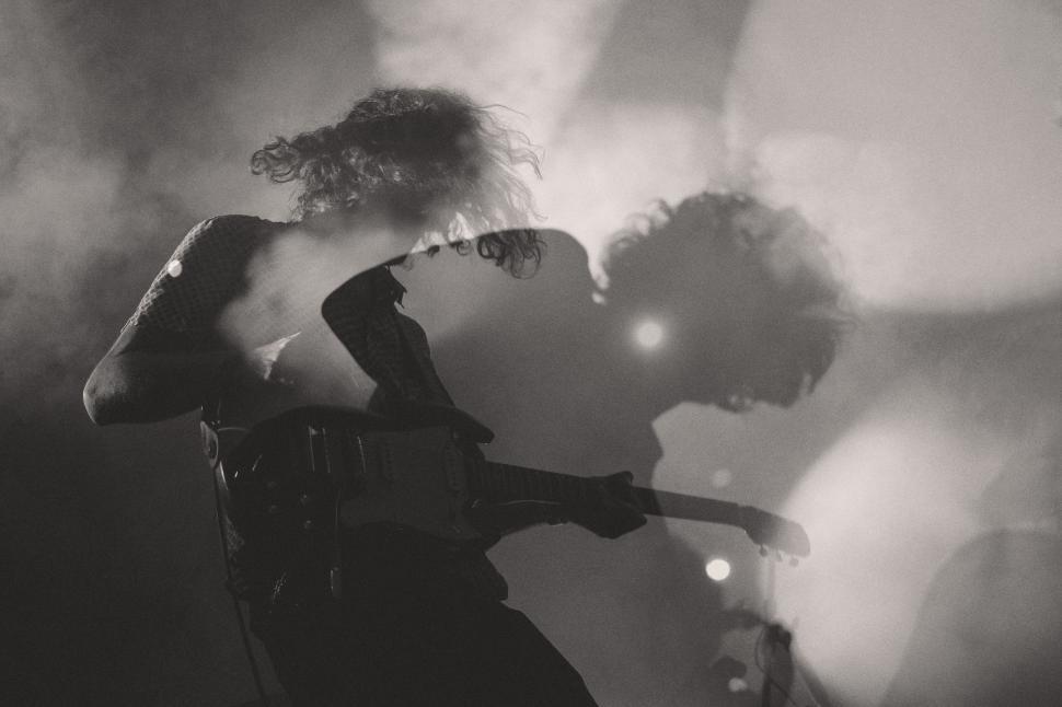 Free Image of Man Standing on Stage Holding Guitar 