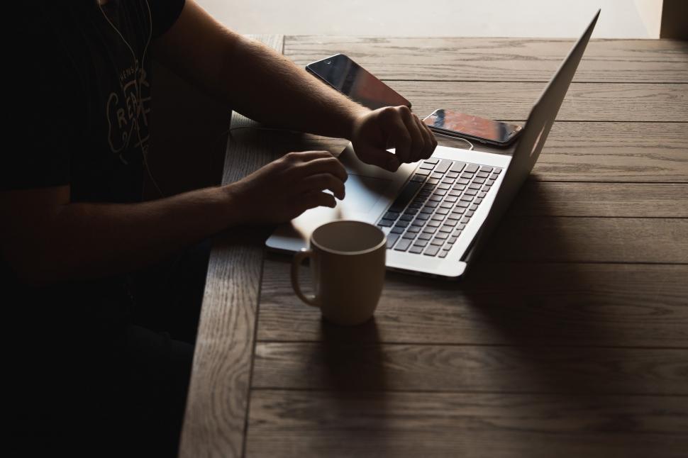 Free Image of Person Using Laptop on Wooden Table 