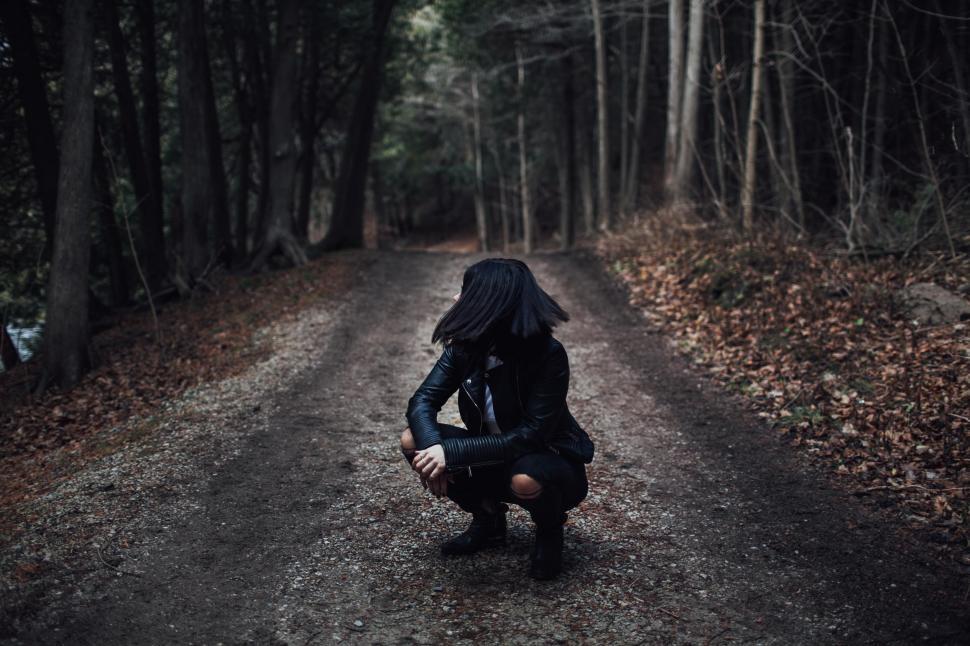 Free Image of Woman Kneeling Down on Dirt Road 