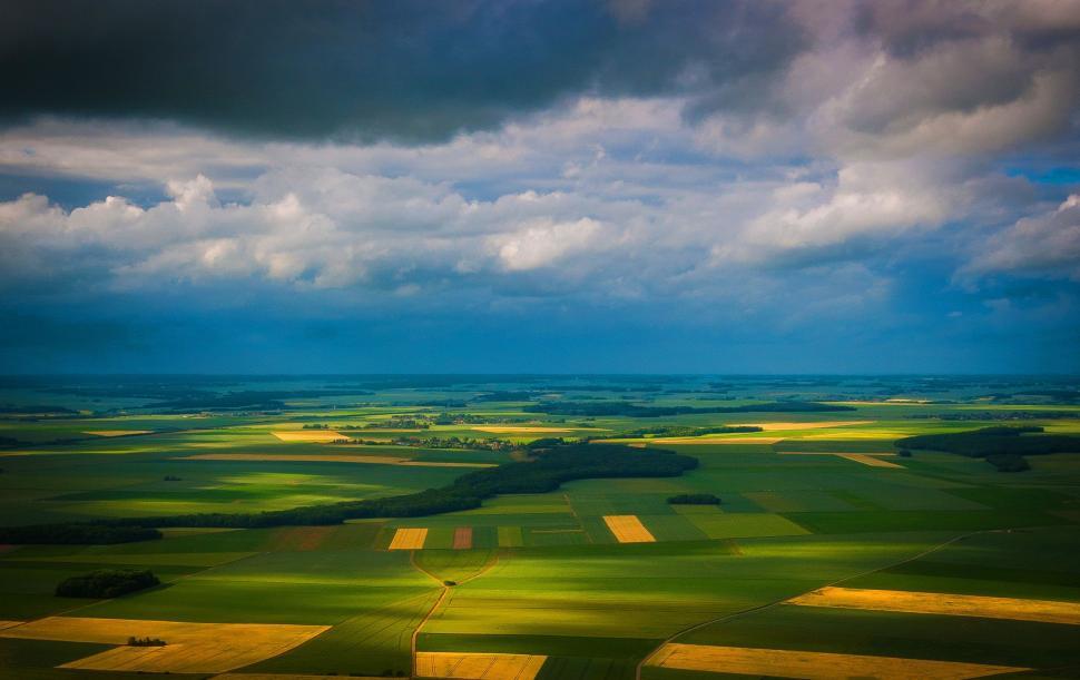 Free Image of Aerial View of Green Field Under Cloudy Sky 