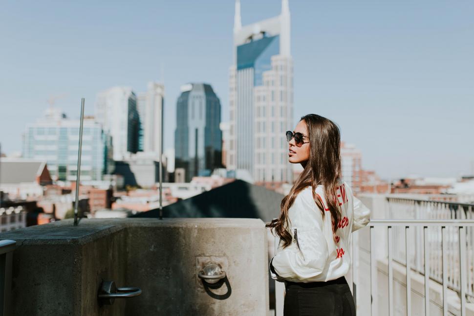 Free Image of Woman Standing on Roof Next to Tall Building 