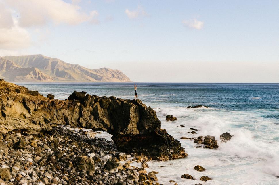 Free Image of Person Standing on Rocky Cliff Overlooking Ocean 