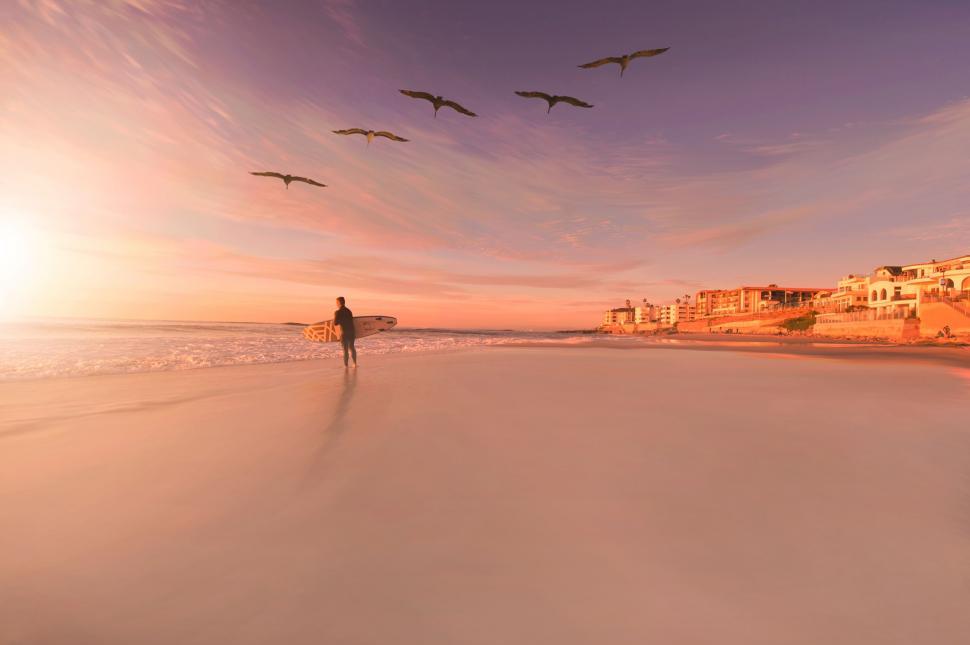 Free Image of Man Walking on Beach With Surfboard 