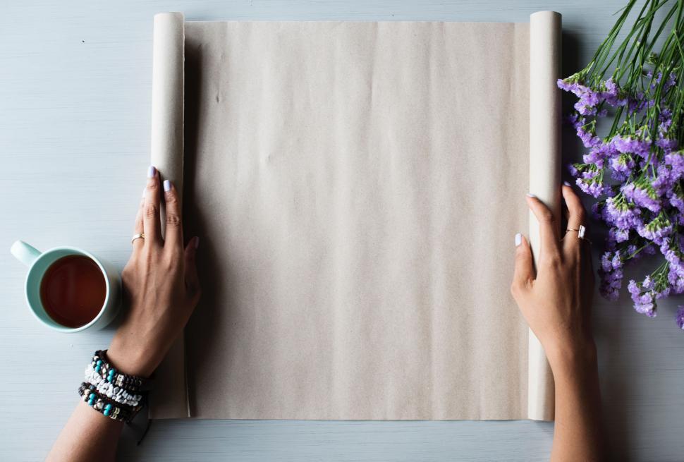 Free Image of Two Hands Holding Paper Next to Coffee Cup 